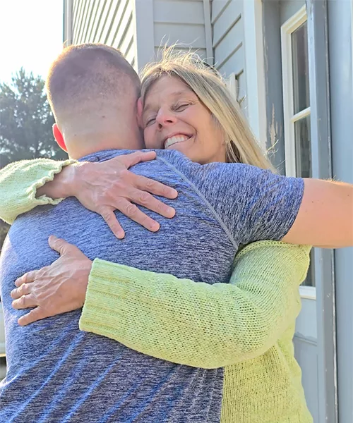 Nicole embracing a man for a hug while smiling