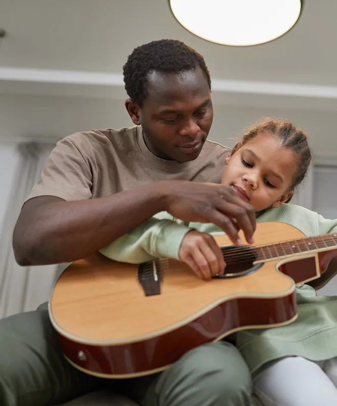 Dad and child playing guitar together